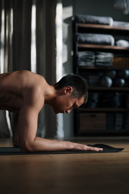 Focused man doing a challenging yoga pose in a well-lit studio